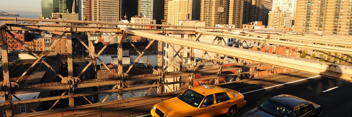 Cars drive along a bridge in a city.