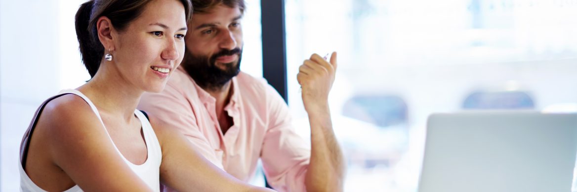 Two people seated looking at a laptop.