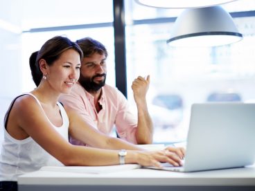 Two people seated looking at a laptop.