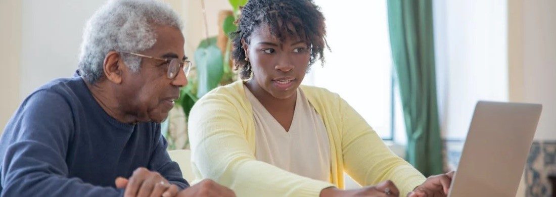 A person assists their grandparent on a computer.