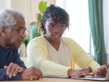 A person assists their grandparent on a computer.