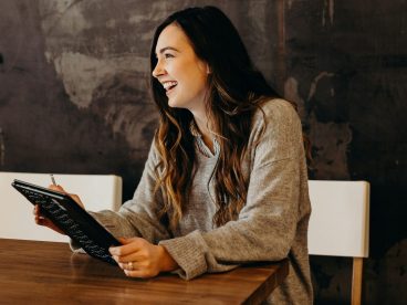 A woman smiles while holding a tablet.