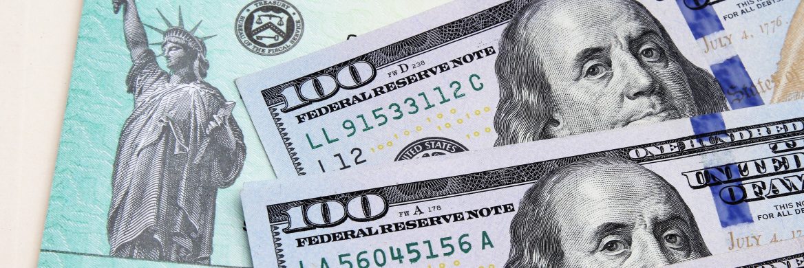 Two one-hundred-dollar bills on top of a stimulus check.