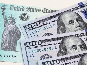 Two one-hundred-dollar bills on top of a stimulus check.