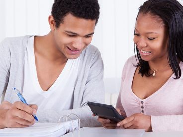 Two people looking at a calculator as they file their taxes.