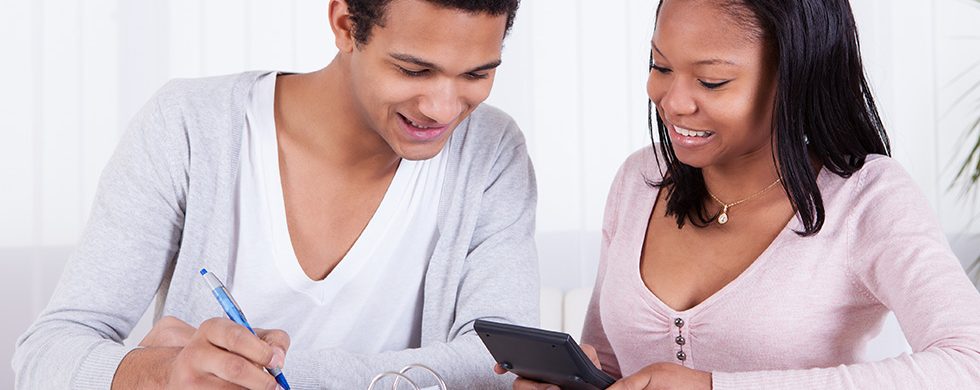Two people looking at a calculator as they file their taxes.