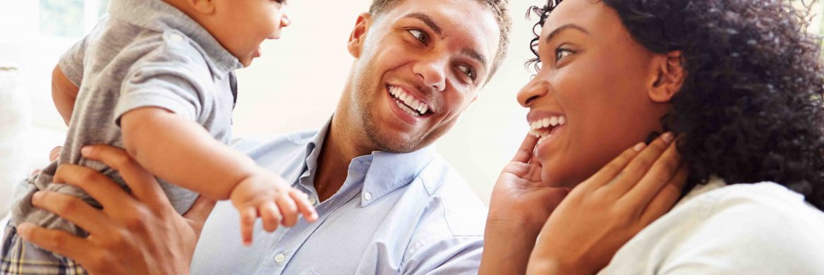 “A father is smiling about being eligible for the Child Tax Credit as he holds his baby up to look at his happy mother.