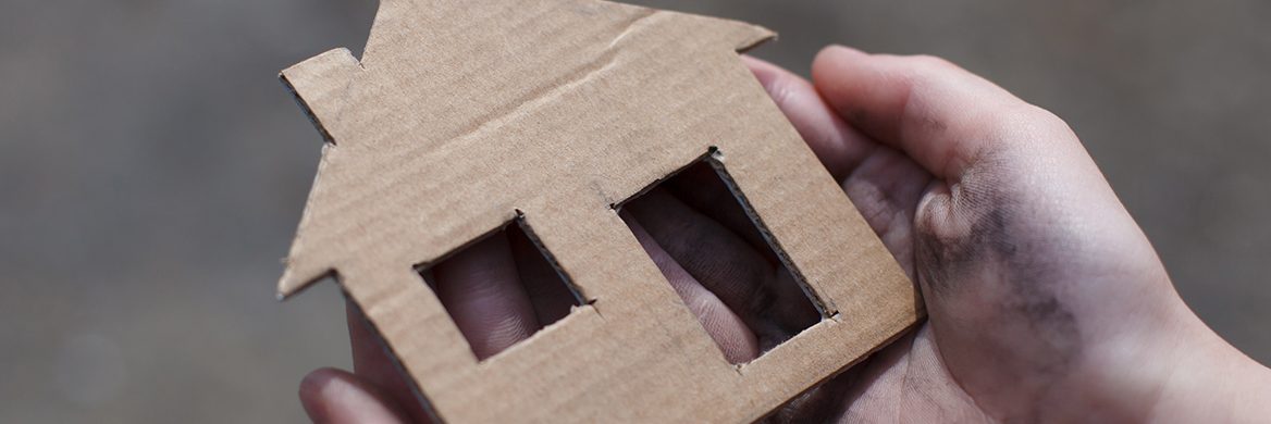 Hands holding a cardboard cutout of a house.