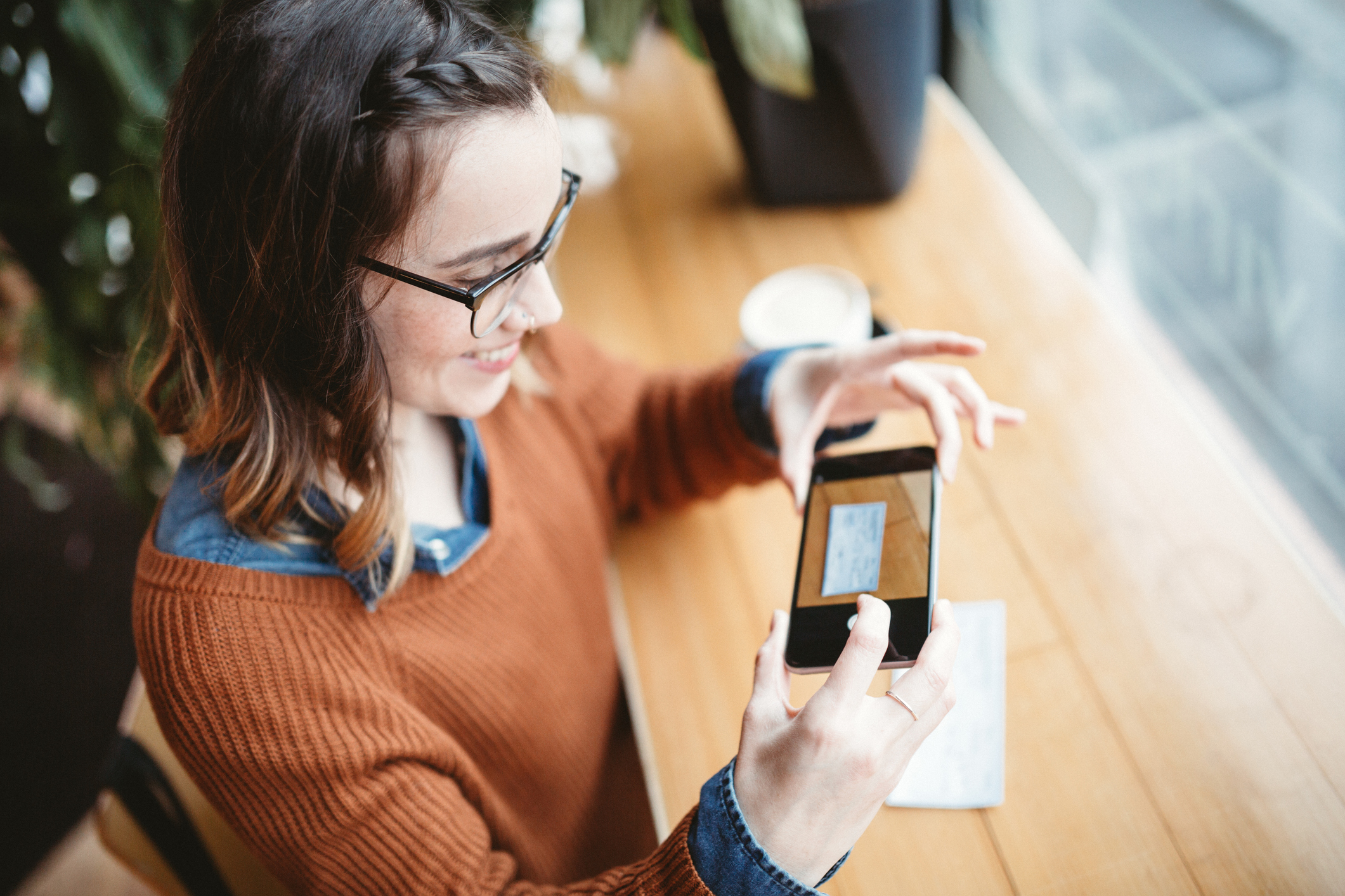 A woman is smiling while taking a picture of a check.