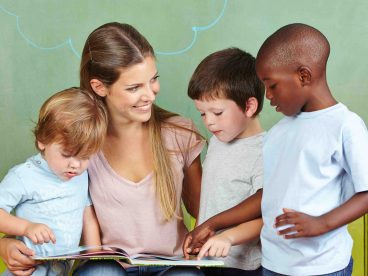 Three children with a childcare worker who helps their families qualify for the Child and Dependent Care Credit.