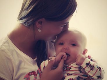 Mother looking away from camera holds her baby in her arms.