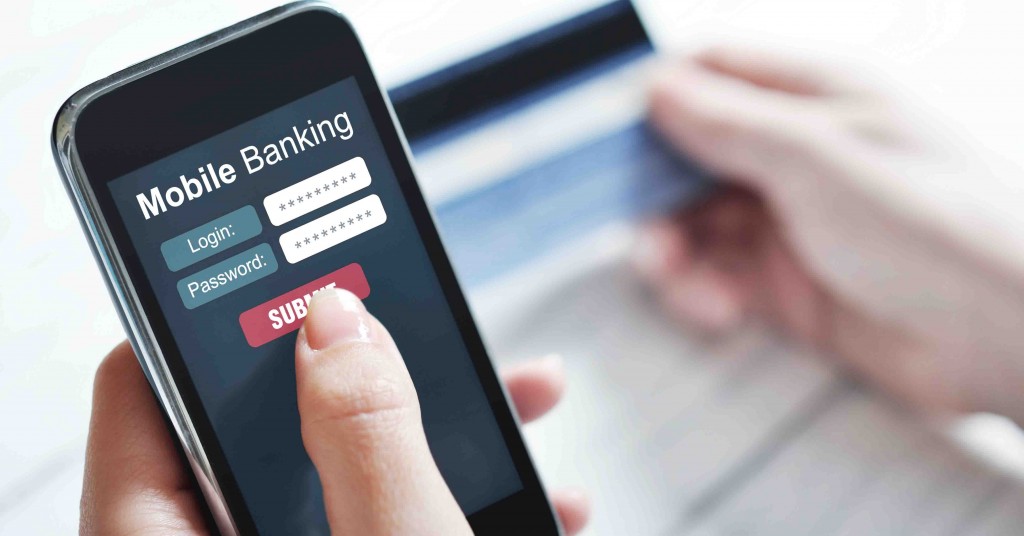 A person logging into a mobile banking account on a cell phone while looking at a debit card.