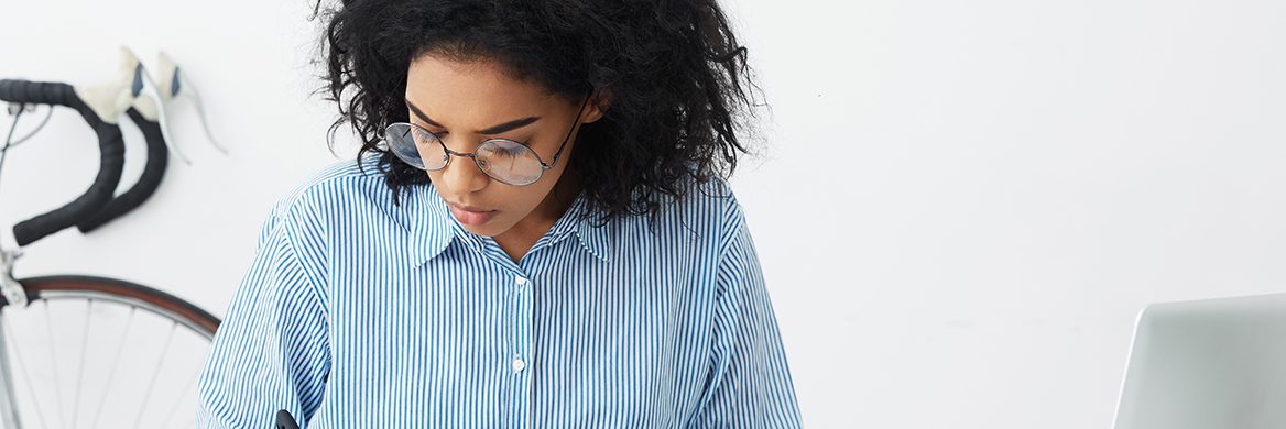 Woman writes in a notebook while using a calculator.