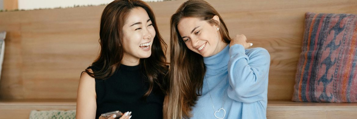 Two women sitting together looking at a laptop screen.