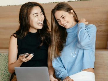 Two women sitting together looking at a laptop screen.