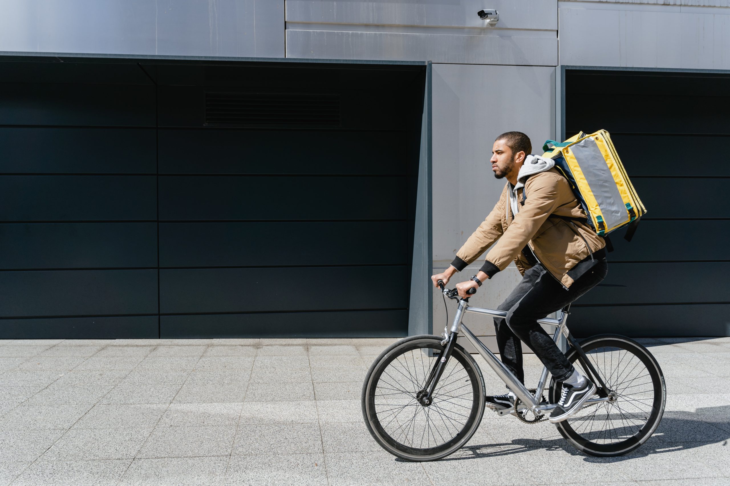 A man with a food delivery backpack riding a bike.