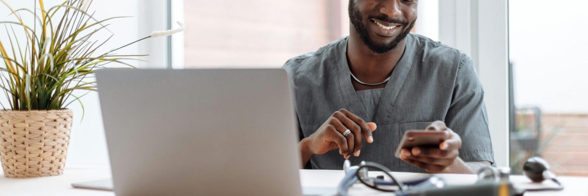 Man looks at his open laptop and phone.