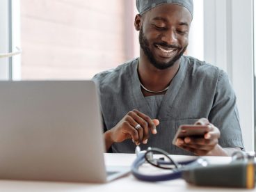 Man looks at his open laptop and phone.
