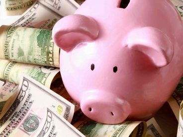 A piggy bank surrounded by cash.