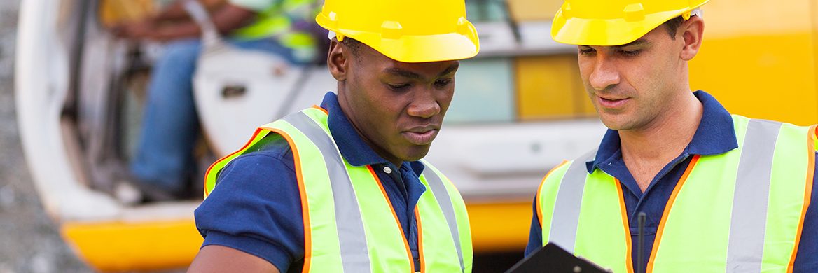 Two workers talk at a construction site.
