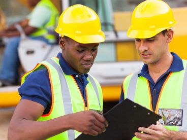Two workers talk at a construction site.