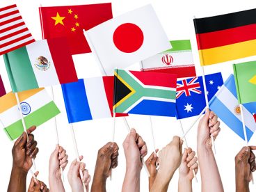 Hands holding up flags from countries around the world.