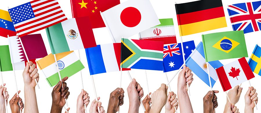 Hands holding up flags from countries around the world.
