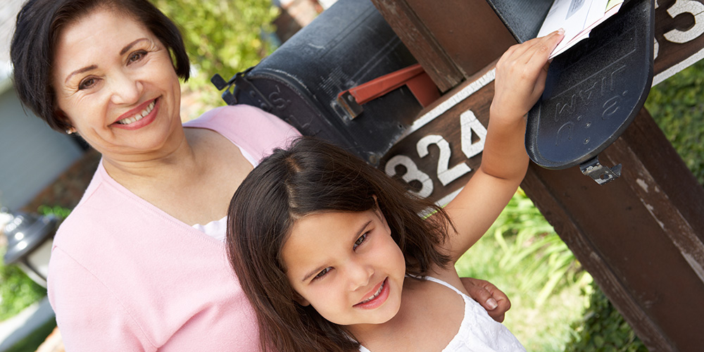 A child and grandparent check the mailbox for mail.
