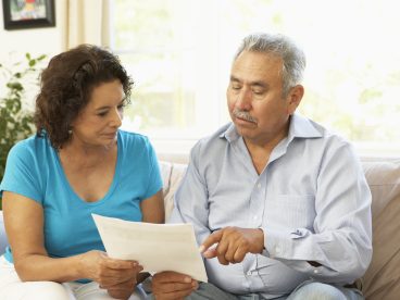 Two people seated on a couch looking at a tax document