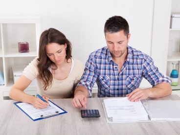 A couple looks at a calculator as they file their taxes.